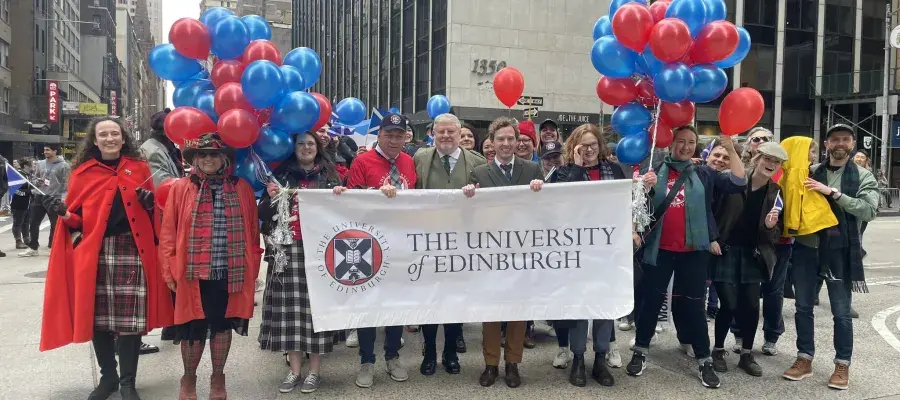 The University of Edinburgh community at the NYC Tartan Day Parade 2024 posing with a University-branded banner 